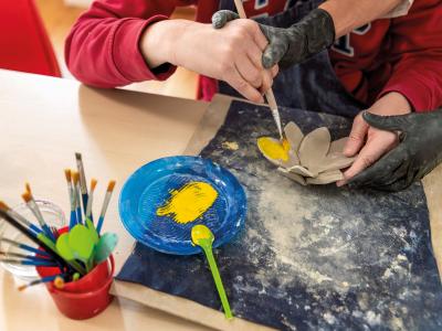 Sul tavolo ingombro di pennelli, un fiore giallo prende colore. Le mani esperte di una volontaria guidano con dolcezza quelle più incerte di una donna durante il laboratorio di ceramica. Nei pomeriggi al Centro Diurno Adulti de iSemprevivi, ogni gesto è cura: esperienze pensate per riattivare mente, mani e relazioni, con il supporto di volontari ed educatori.